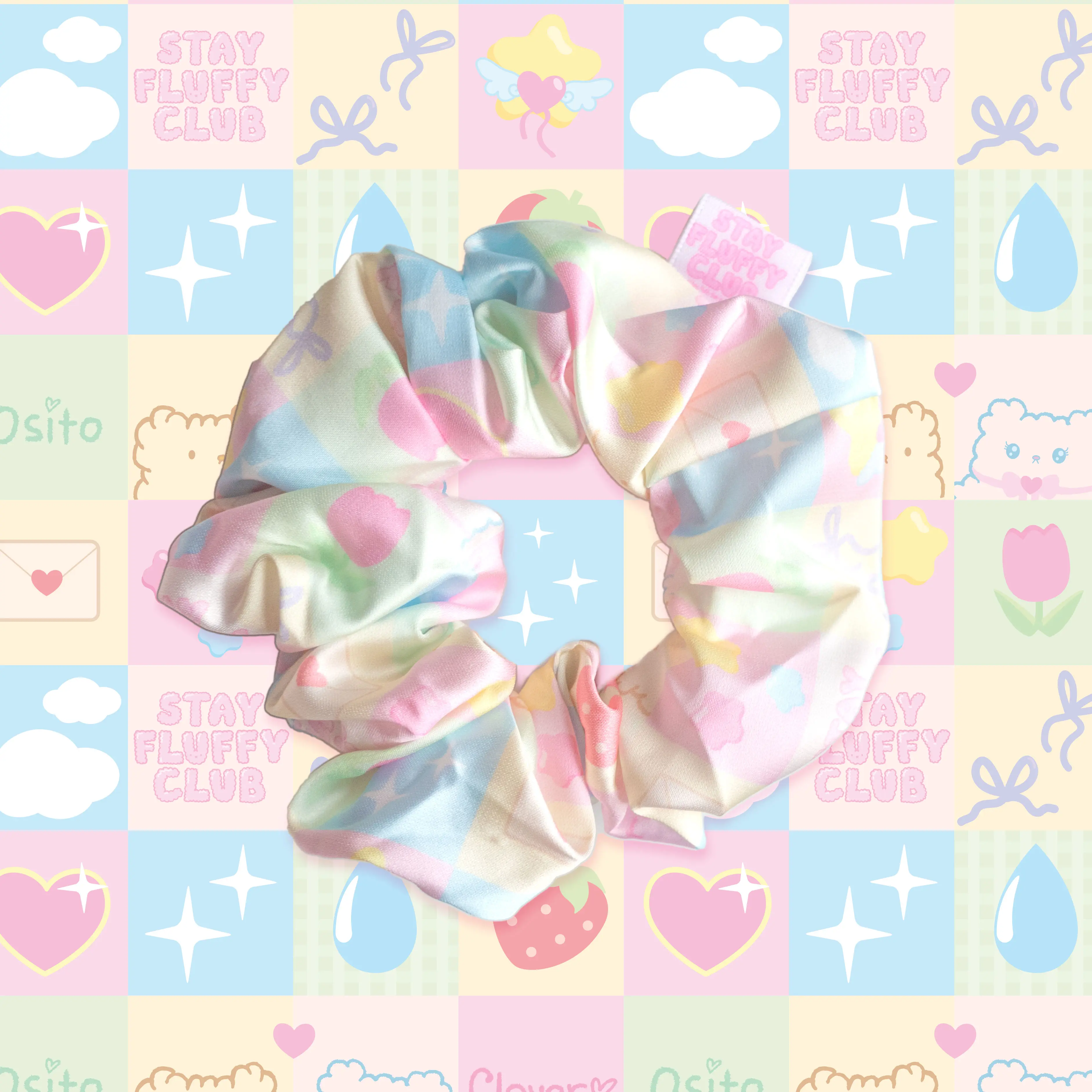 Pastel Stay Fluffy Club scrunchie on a colorful quilt-pattern background